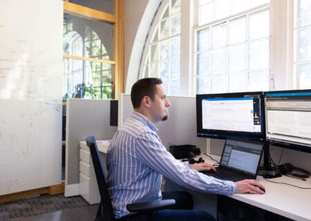 Man sits at his desk at Prendio, working on his computer.